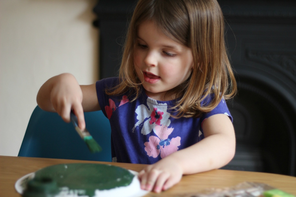 A little girl painting a paper plate for a St George's Day craft