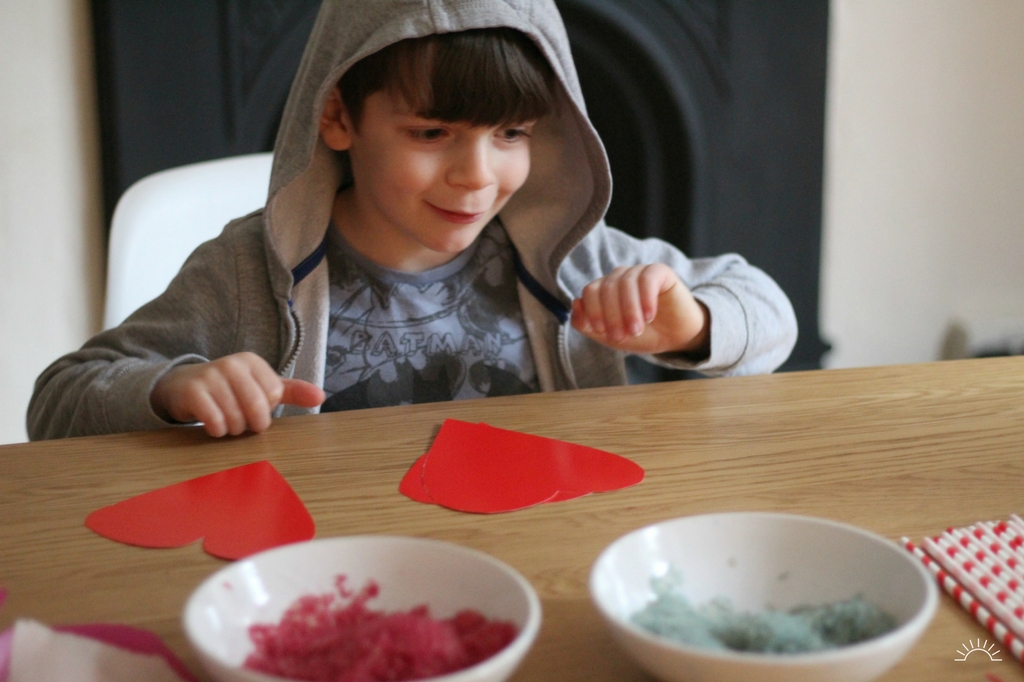 A boy ready to decorate his Valentines crafts hearts