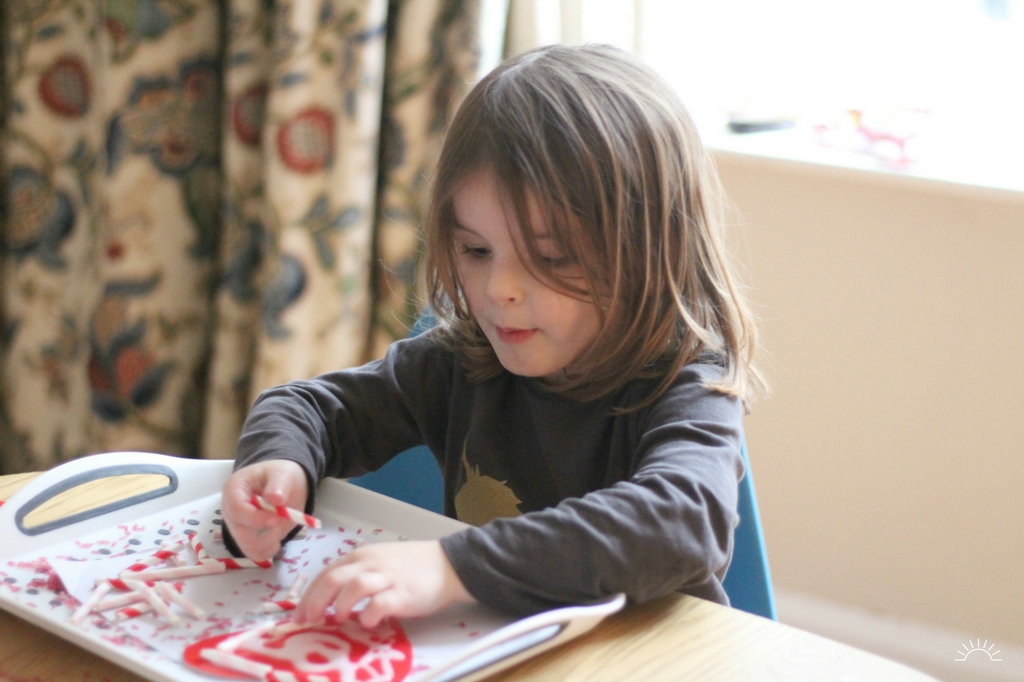 A girl sticking straws to her heart Valentines craft