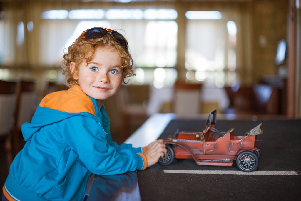 Blue-eyed boy with a model vintage car