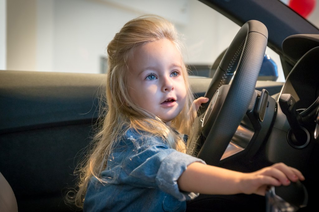 Little blond girl behind the steering wheel