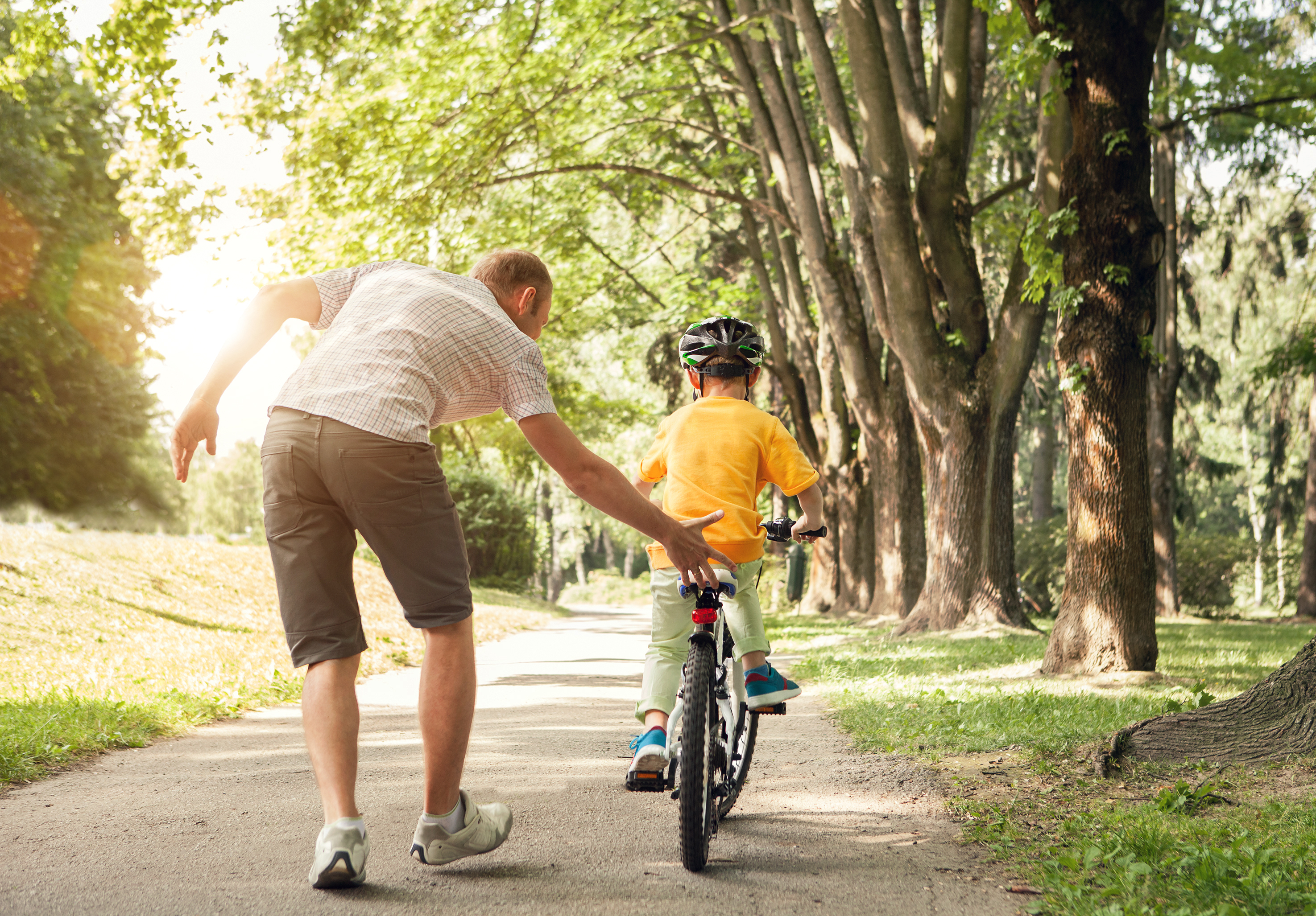 A man helping a little boy ride a bike
